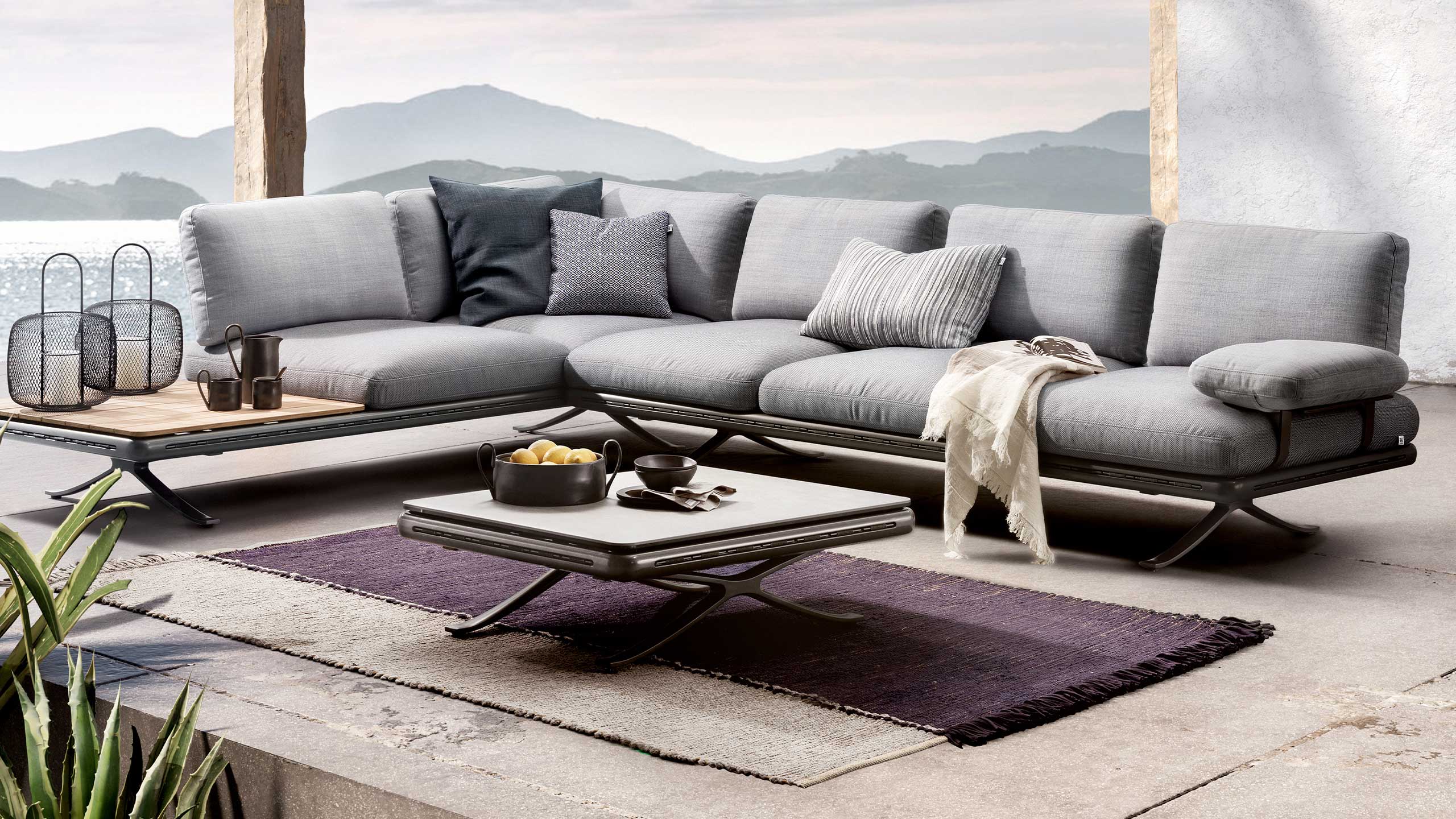 rolf benz outdoor sofa yoko vor einem couchtisch mit lila outdoor teppich auf einer stein terrasse