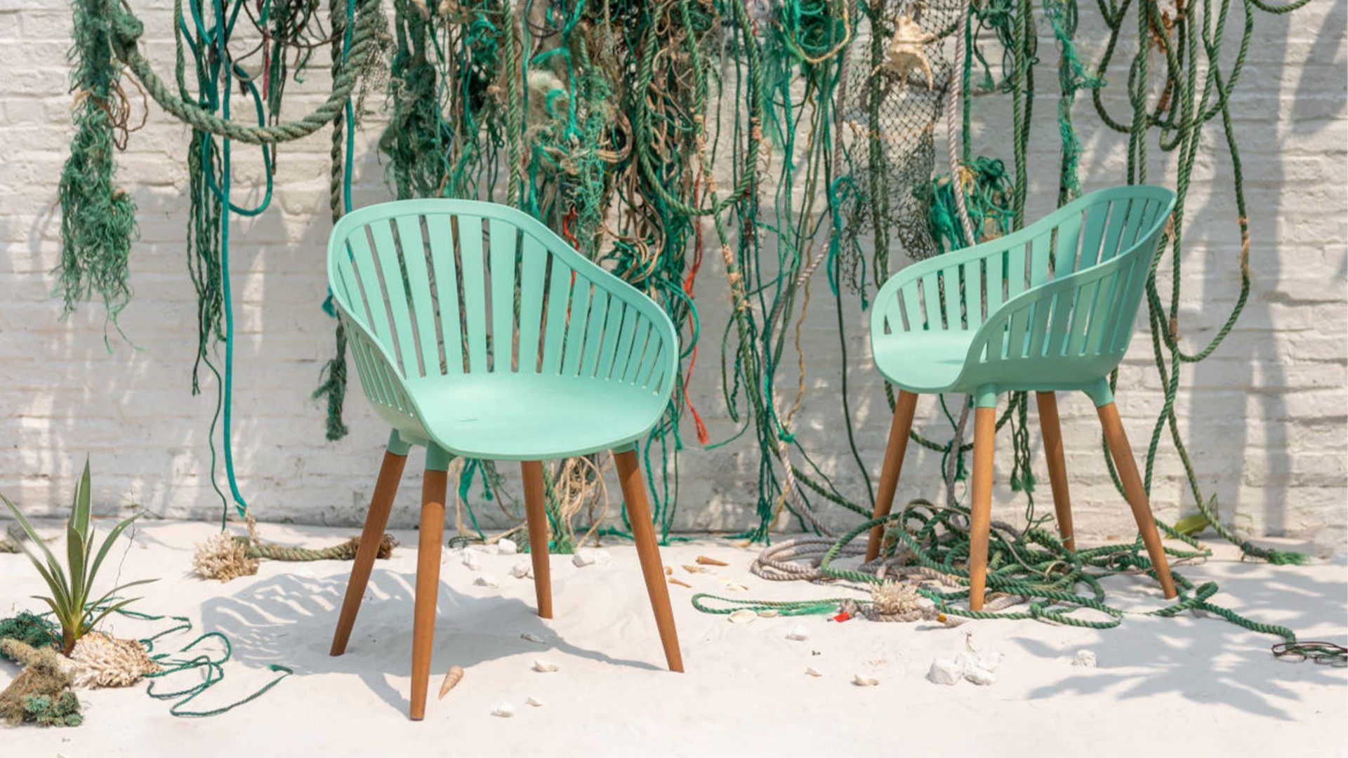 zwei lifestylegarden nassau outdoorstühle in türkis vor grünen und türkisblauen fischerseilen